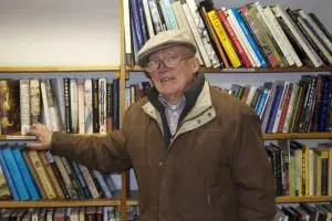 Frank Volkmann stands before his soon-to-disappear bookshelves. Photo by K.E. Foley
