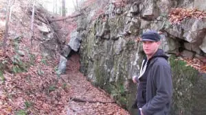 Kelly stands near the entrance to the Hamilton Mine. A piece of an old narrow-gauge rail is visible between him and the mine opening. Photo by M. Turton