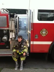 A junior firefighter suits up in training gear.