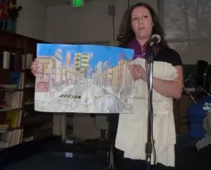 During a plea to the board to maintain the program, Haldane parent Cindy Chiera displays artwork her son made at school.