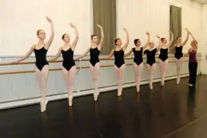 A teacher makes an adjustment on a student in a ballet class in the studio at Ballet Arts.