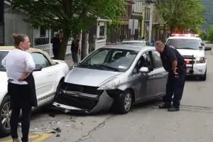 CSPD Officer Ed Boulanger speaks with the driver of a car that smashed into a vehicle parked on Main Street on Tuesday morning. Sharon Tiffany, owner of the car that was struck, looks on.