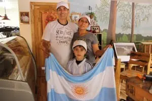 Rincon Argentino's proprietors, Marco and Ramona Antonio, with their son Ivan, holding up an Argentinian flag at their new café.