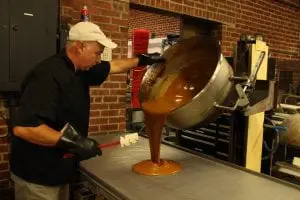 Terry Craft, master chocolatier and co-owner of Alps Sweet Shop, pours 110 pounds of salted caramel onto a cooling tray at their Beacon location. (Photo by M.A. Ebner) 