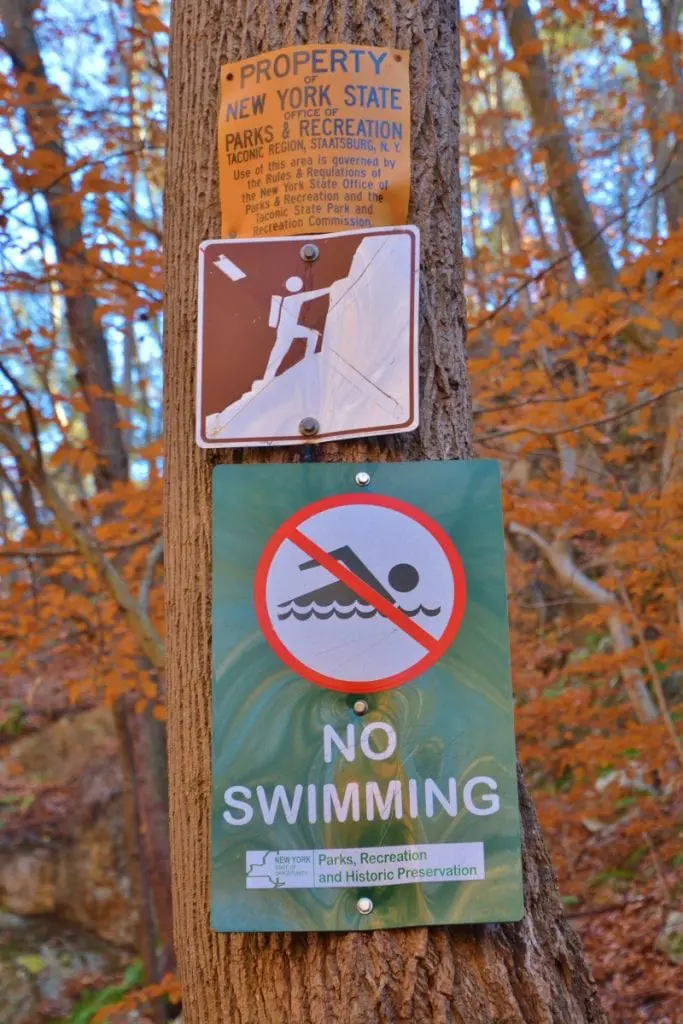 The New York State park system forbids swimming and climbing rocks at Indian Brook Falls, but the sign prohibiting rock-climbing no longer bears the red diagonal slash indicating a ban. (Photo by L.S. Armstrong)