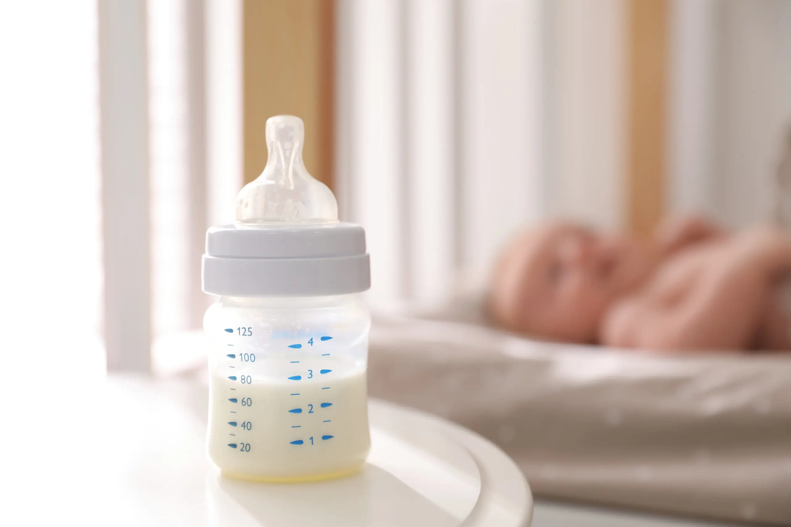 Healthy baby sleeping in cot, focus on bottle with milk