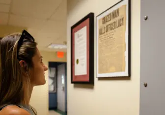 A descendant of Officer Lucy reads a 1922 news clipping at the Beacon Police Department about his death. Photo by Valerie Shively