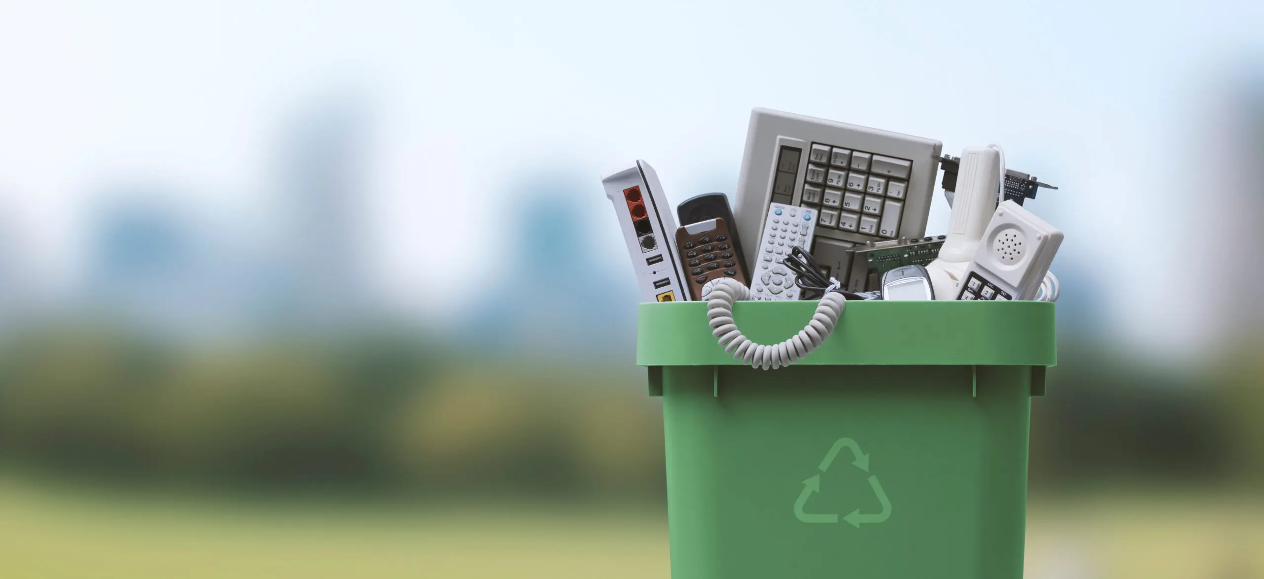 Waste bin full of electronics, e-waste and recycling concept computers keyboards phones
