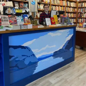 Herman’s painting on the counter at Split Rock Books in Cold Spring, with co-owner Michael Bender