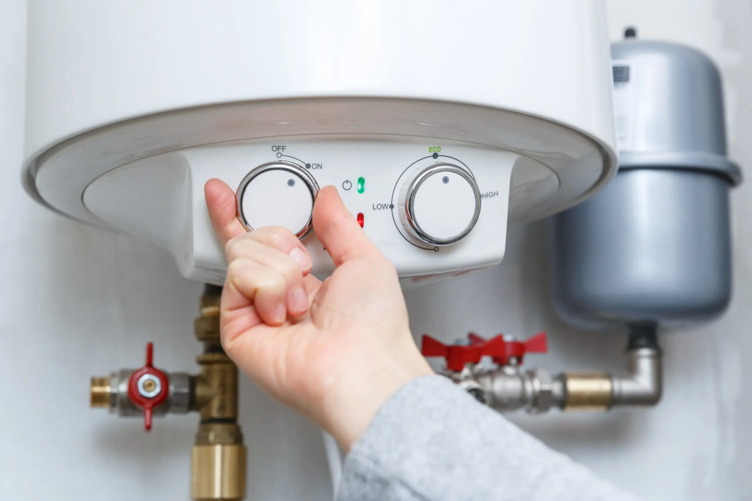 Female hand turning on electric water heater (boiler). Household enegry saving equipment