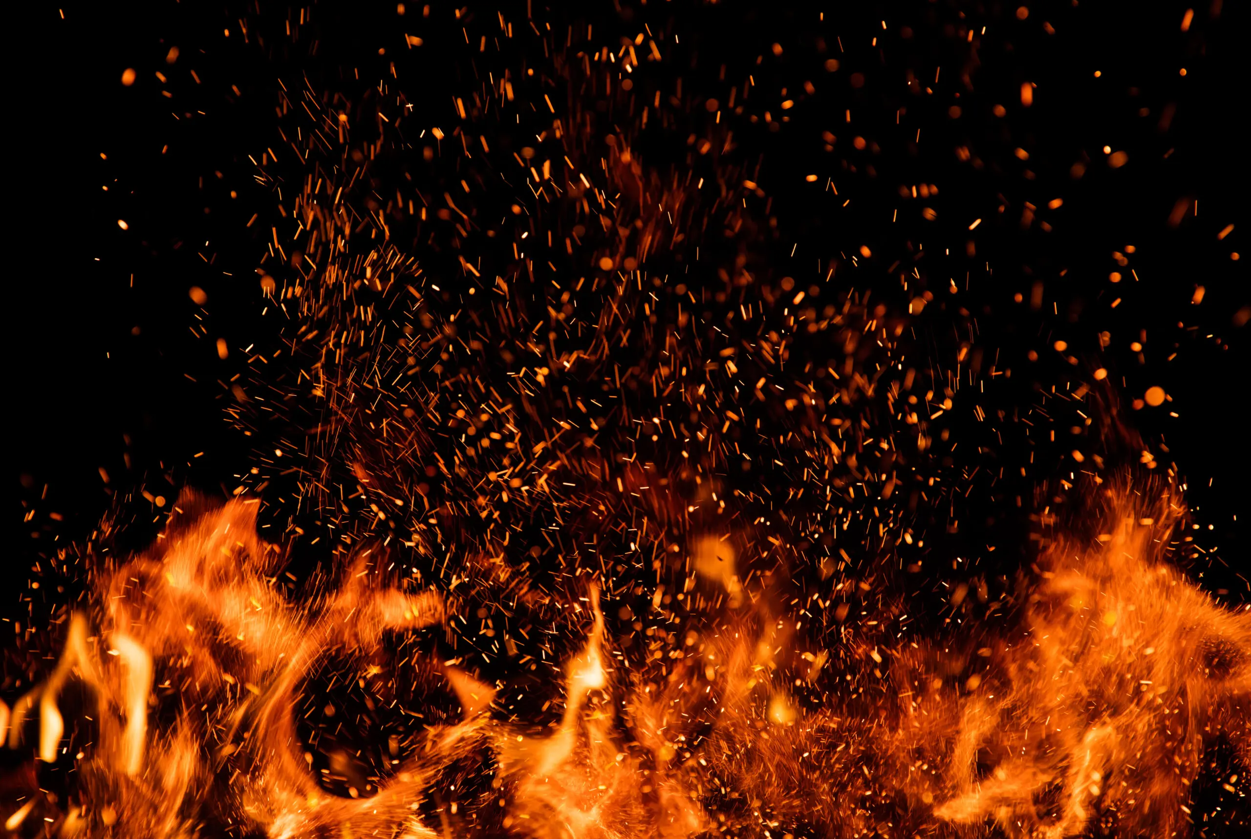 Detail of fire sparks isolated on black background. Abstract flaming background
