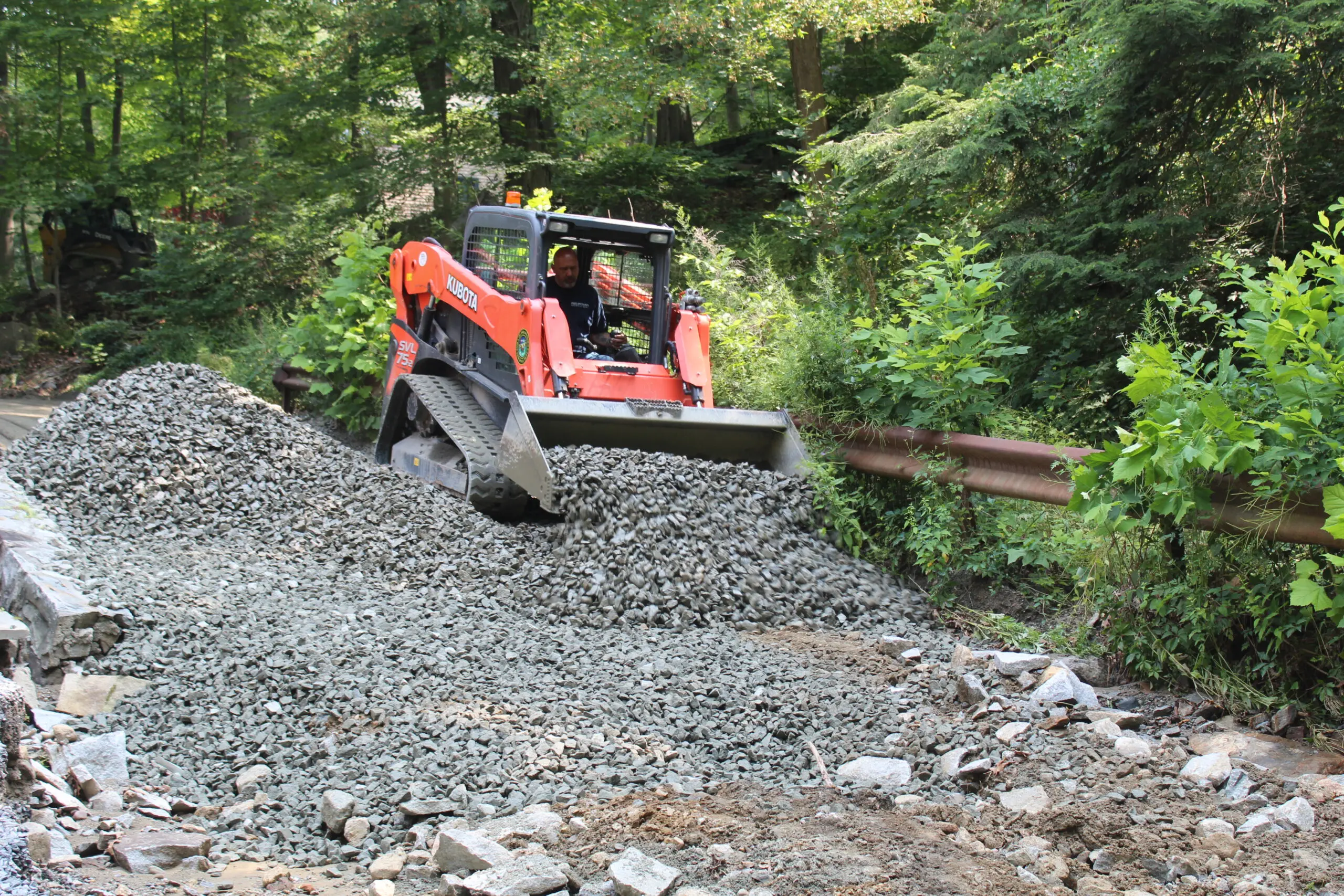 Adam Hotaling, Philipstown’s highway superintendent, spreads gravel on a storm-damaged section of Old Manitou Road. (Photo by L. Sparks)