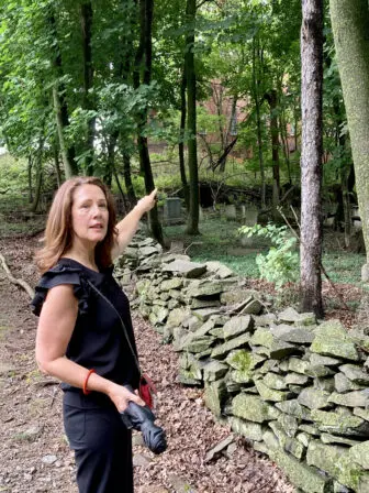 Shelley Simmons-Bloom points to the historic but overgrown cemetery behind the Prophecy site.