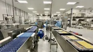 An employee watches an assembly line at Cafe Spice’s new Beacon facility.