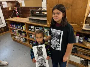 Hazel Augello, 4, and Atticus Perez, 11, pose at the Garrison Art Center. Hazel has a print and Atticus is wearing a Beacon Bonfire T-shirt.