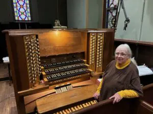 Barbara Lusk poses with the St. Mary's organ that her late husband refurbished.