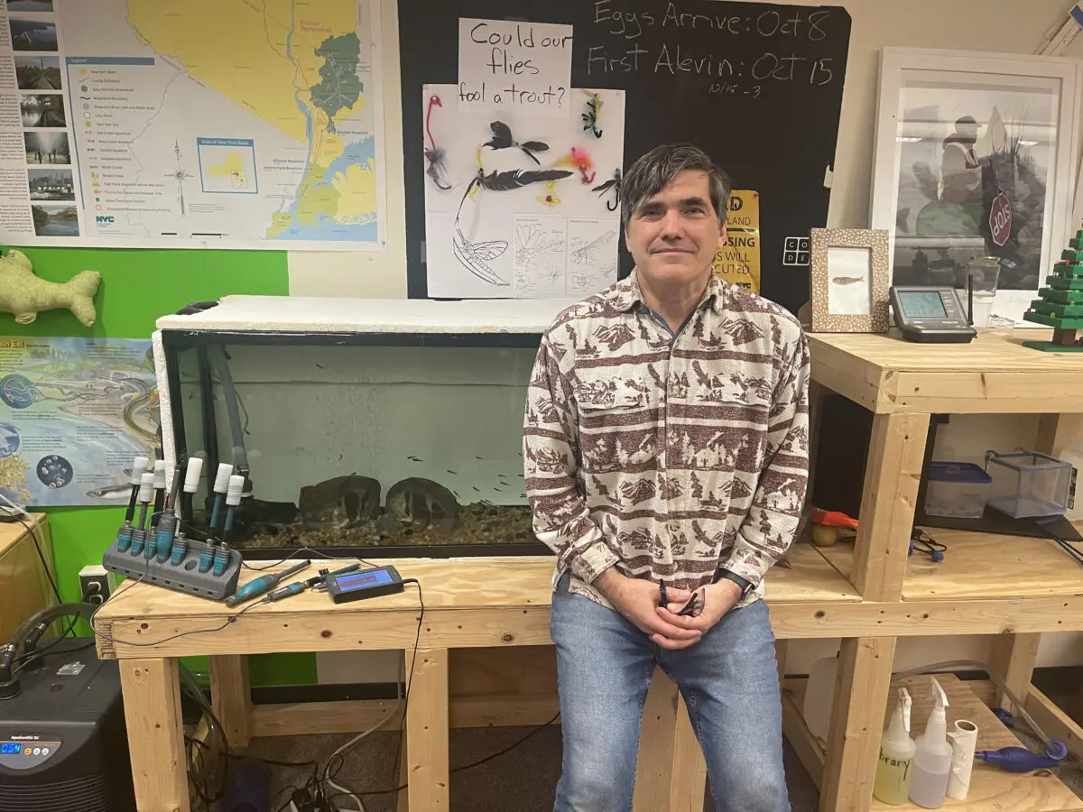 Aaron Burke of South Avenue Elementary in Beacon sits in front of an aquarium filled with trout minnows that his students will disperse. Photo by J. Asher
