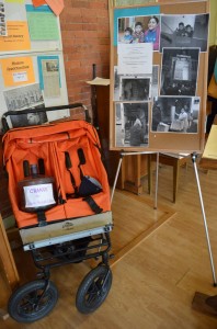 A poster in First Presbyterian's hall depicts their project to help a mother and her two children dislocated by Hurricane Sandy; a stroller recently acquired for the family is displayed alongside. (Photo by J. Tao)