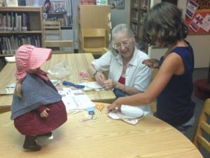 Beverly Barker assisting an attendee with needlepoint.