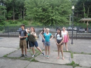 The large cast breaks into smaller groups and one group rehearses outside the theater.
