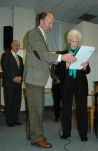 Supervisor RIchard Shea presents a plaque of gratitude to Betty Budney, who retires from the Town Board this month; fellow board member John Van Tassel pictured in background. Photo by L.S. Armstrong