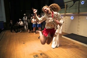 Leandra Rice jumps for joy at a recent Anything Goes rehearsal, as sailors and chorus girls look on.  (Photo by Jim Mechalakos)