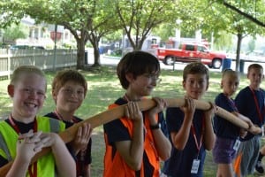 Junior firefighters support a fire hose while platoon members spray.