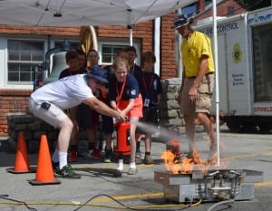 One junior firefighter platoon practices spraying a fire extinguisher at a controlled blaze.