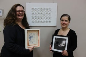 Kat Stoutenborough and Michelle Rivas, director of the exhibit space at the Howland Public Library, holding their works featured in the CoMFY exhibit (photo by A. Rooney)