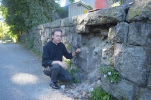 Father Shane Scott-Hamblen of St. Mary's is shown at a spot where the wall has already collapsed. (Photo by M. Turton)