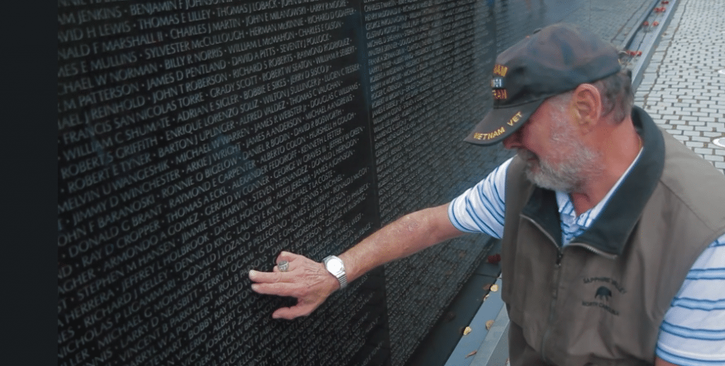 Mike Mastrolia rubs the name of Roy Parson of Perkins, Oklahoma, who died with 10 other soldiers in a helicopter crash in Vietnam in 1968. (Photo by Greg Gunder)