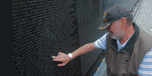 Mike Mastrolia rubs the name of Roy Parson of Perkins, Oklahoma, who died with 10 other soldiers in a helicopter crash in Vietnam in 1968. (Photo by Greg Gunder)