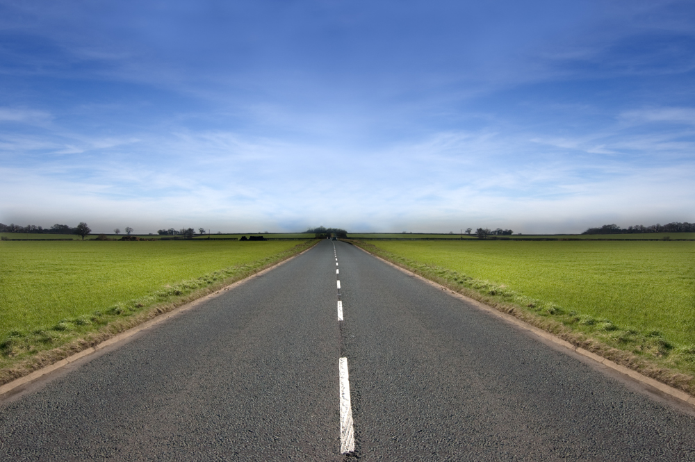 Long road stretching out into the distance under a dramatic blue sky