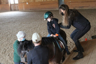 Flint Reeves of Beacon is helped onto a horse at the Topfield Center in Philipstown.