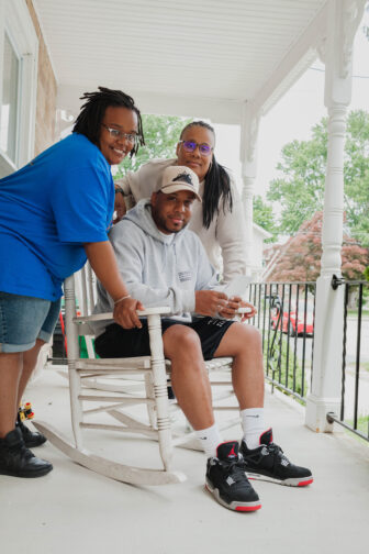 Ed McNair Jr., surrounded by his sisters, LaKeshia and LaVonne, sits in his mother’s favorite rocking chair at the family’s Hubert Street home.