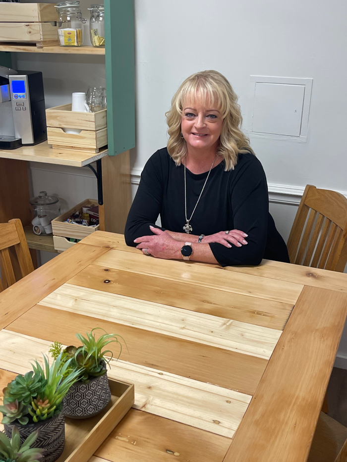 usti Callo sits at a table she made for the faculty lounge from boards reclaimed during a recent renovation at the school. Photo by J. Asher