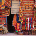 A photo by Jon Arnold of a carpet shop in Essaouira, Morocco, is accompanied in Why We Travel by a quote from Joyce Meyer: “Patience is not the ability to wait, but the ability to keep a good attitude while waiting.”