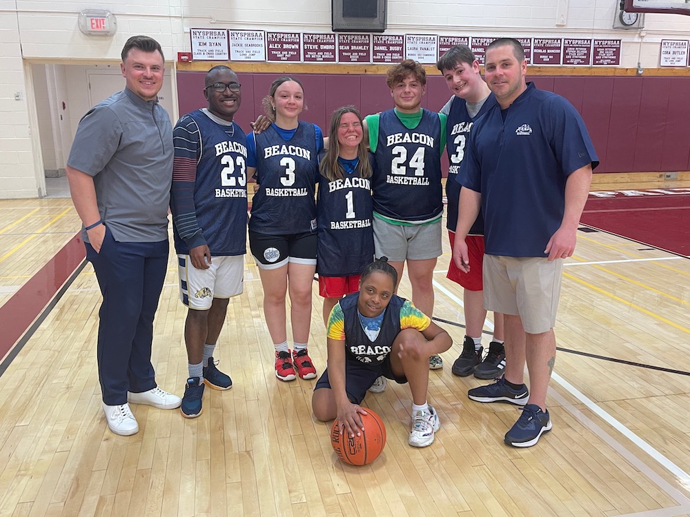 Members of the Beacon Unified Sports basketball team are shown at the New Paltz gym with Patrick Schetter (left), the Beacon boys' varsity basketball coach, and Michael Mullins (right), head coach for Unified Sports. Photo by J. Asher