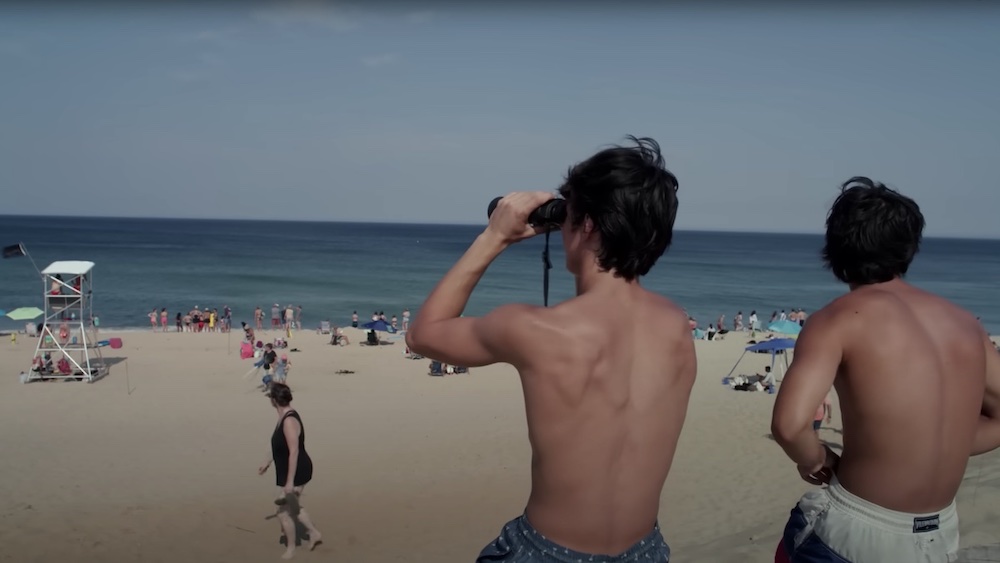 In a still from After the Bite, beachgoers scan the water for sharks.