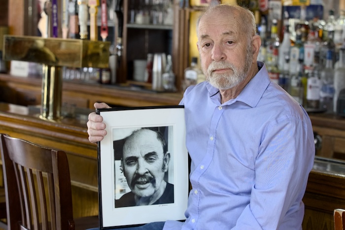 Richie Kaplan of Max's on Main posed this week with a photo of his brother, Harvey, who died last year. They opened the bar and restaurant in 2006. Photo by Ross Corsair