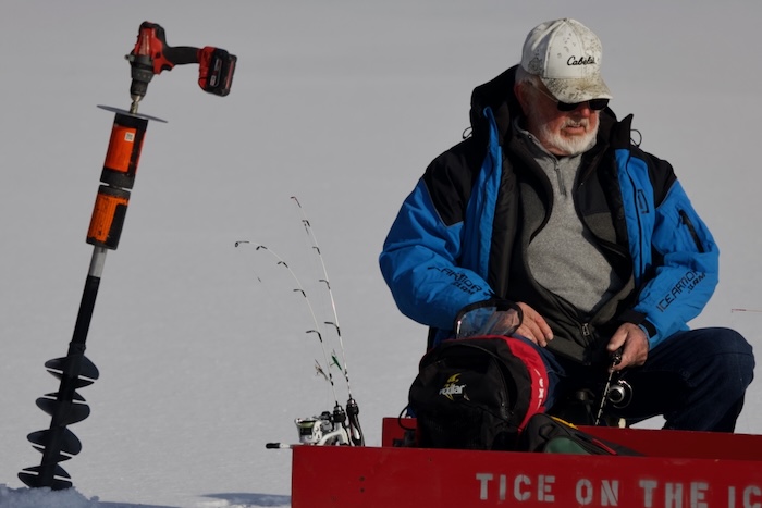 Tice sits with his sled, which reads “Tice on the Ice,” his rods and a drill-powered auger.