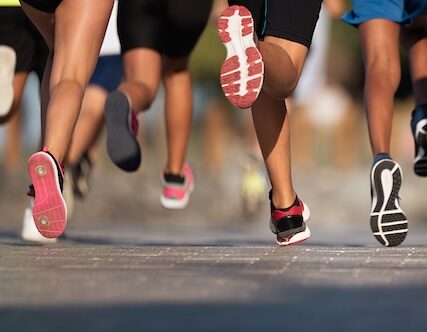 Running children, young athletes run in a kids run race,running on city road detail on legs,running in the light of morning