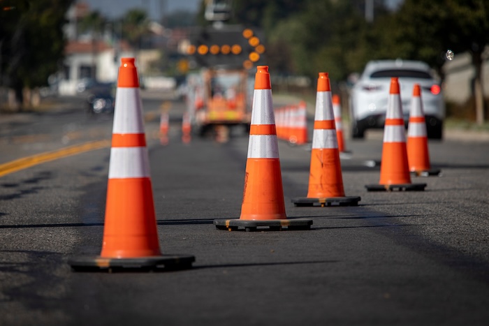 Traffic cones on road with electronic arrow pointing to the right to divert traffic and white car in distance construction road work roadwork