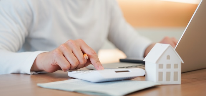 close up young man hand press on calculator to check and summary expense of home loan mortgage for refinance plan , people lifestyle concept tax star rebate check