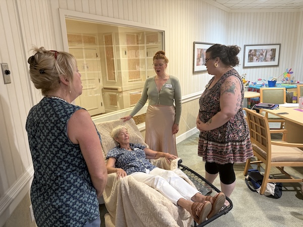 From left: Patti Cooper, Donna Reilly (in chair), Ryn Fink and Clara Masters. The choir practices with one member assuming the role of the patient.